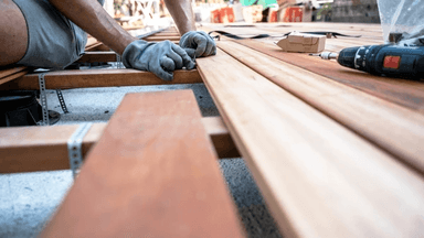 A worker assembling wooden deck planks.