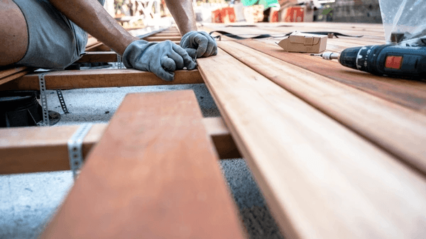 A worker assembling wooden deck planks.